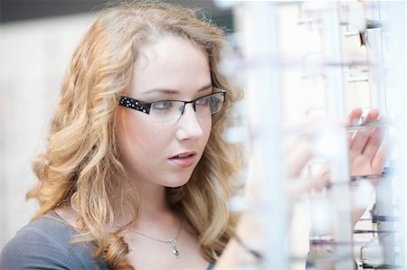 simsearch:6109-08204459,k - Young woman looking at eyeglasses display Stock Photo - Premium Royalty-Free, Code: 649-07063761