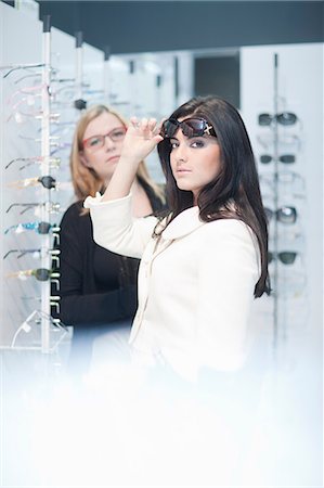 saleswoman customer - Young woman trying on sunglasses in opticians shop Stock Photo - Premium Royalty-Free, Code: 649-07063799