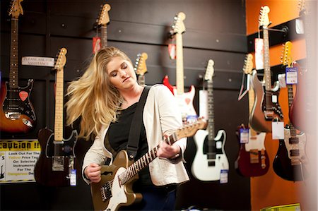 person playing electric guitar - Young woman testing guitar in music store Stock Photo - Premium Royalty-Free, Code: 649-07063818