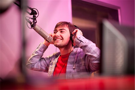 radio - Young man broadcasting in recording studio, smiling Stock Photo - Premium Royalty-Free, Code: 649-07063941