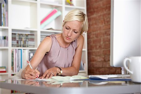 designer (interior, female) - Mid adult woman making notes at desk Stock Photo - Premium Royalty-Free, Code: 649-07118324