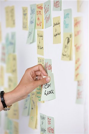 post it - Woman's hand sticking adhesive note saying teamwork on wall Stock Photo - Premium Royalty-Free, Code: 649-07118374
