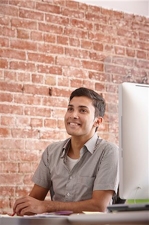 Portrait of young man at desk with brick wall Stock Photo - Premium Royalty-Free, Code: 649-07118379