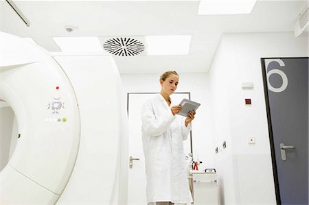 female doctor serious - Female doctor looking at digital tablet in treatment room Foto de stock - Sin royalties Premium, Código: 649-07118637