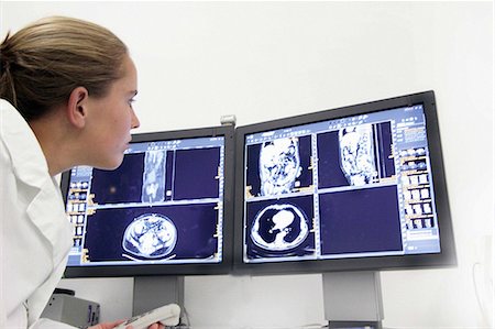 female doctor serious - Female doctor examining ct scans on computer monitors Foto de stock - Sin royalties Premium, Código: 649-07118642