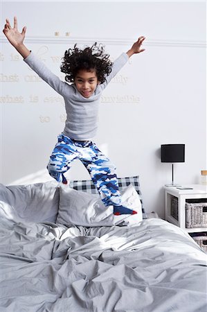 Boy jumping on bed with arms up Foto de stock - Sin royalties Premium, Código: 649-07118964