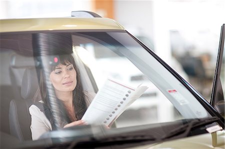 reflection of woman in car - Mid adult woman reading car brochure in showroom Stock Photo - Premium Royalty-Free, Code: 649-07119129