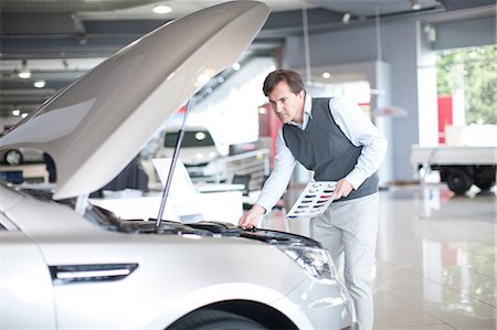 simsearch:649-07119137,k - Mid adult man checking car bonnet in showroom Stock Photo - Premium Royalty-Free, Code: 649-07119138