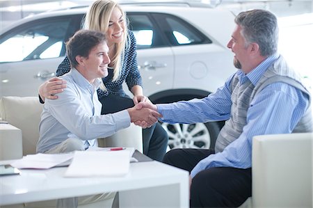 selling a car - Car salesman and couple shaking hands in car showroom Photographie de stock - Premium Libres de Droits, Code: 649-07119150