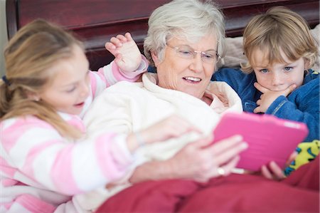 Grandmother and grandchildren playing digital game in bed Stock Photo - Premium Royalty-Free, Code: 649-07119268