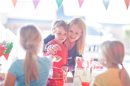 family sitting at table - Two young sisters selling drink to brother and mother Stock Photo - Premium Royalty-Free, Code: 649-07119283