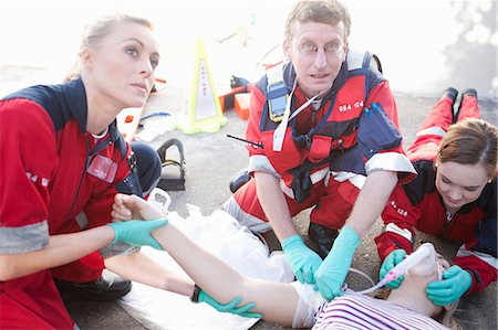 Three paramedics tending patient lying on road Photographie de stock - Premium Libres de Droits, Code: 649-07119307