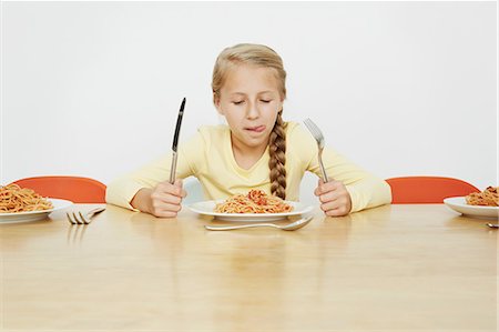 Girl sitting at table with plate full of spaghetti Photographie de stock - Premium Libres de Droits, Code: 649-07119720