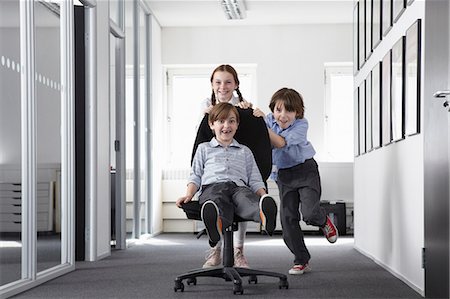 Three children playing in office corridor on office chair Photographie de stock - Premium Libres de Droits, Code: 649-07119771