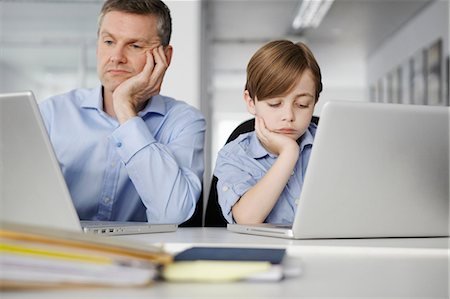 Father and son using laptops looking bored Photographie de stock - Premium Libres de Droits, Code: 649-07119816