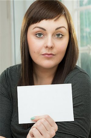 Serious young woman with a blank card Photographie de stock - Premium Libres de Droits, Code: 649-07238234