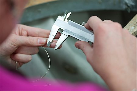 Woman measuring metal wire for jewelry Stock Photo - Premium Royalty-Free, Code: 649-07238391