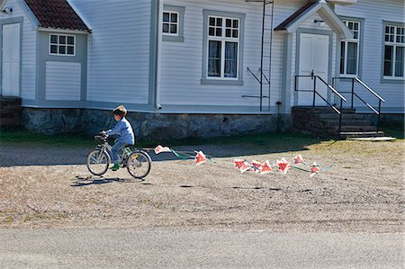 simsearch:649-07238451,k - Boy riding bicycle pulling bunting Foto de stock - Sin royalties Premium, Código: 649-07238459