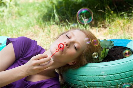 soplando burbujas - Woman lying on tire blowing bubbles Foto de stock - Sin royalties Premium, Código: 649-07238521