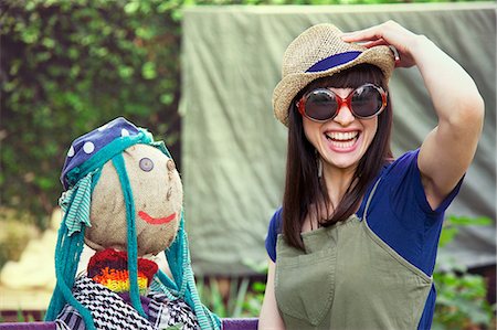 Woman wearing sunglasses and hat with scarecrow Stock Photo - Premium Royalty-Free, Code: 649-07238536