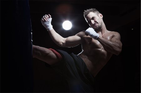 excercise black background - Boxer kicking punch bag Stock Photo - Premium Royalty-Free, Code: 649-07238775