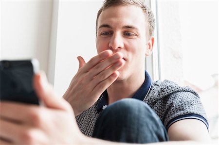 Man blowing kiss at mobile phone Stock Photo - Premium Royalty-Free, Code: 649-07238829