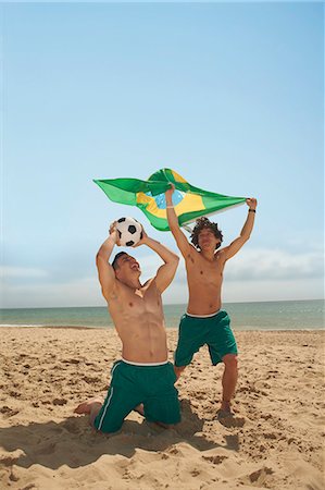 football kneeling - Men holding up brazilian flag on beach Stock Photo - Premium Royalty-Free, Code: 649-07238853