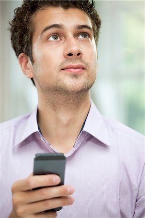 simsearch:649-07238918,k - Young man looking up from mobile phone Stock Photo - Premium Royalty-Free, Code: 649-07238919