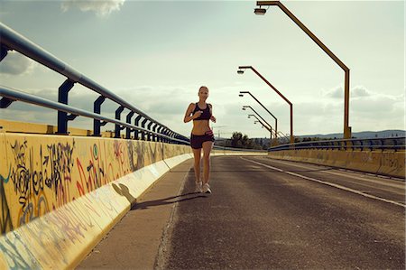 runner from below - Young female jogger running on bridge Stock Photo - Premium Royalty-Free, Code: 649-07238959