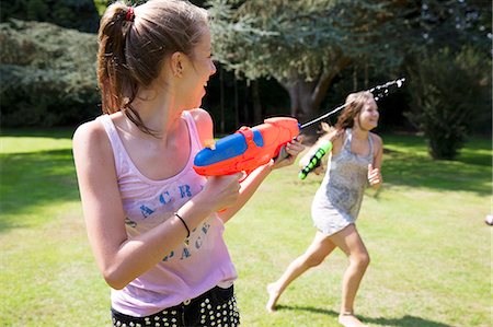 Two teenage girls playing with water guns in garden Photographie de stock - Premium Libres de Droits, Code: 649-07239178