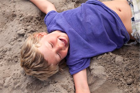 smile laugh summer - Boy lying on sand laughing, Wales, UK Stock Photo - Premium Royalty-Free, Code: 649-07239485