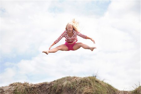 Teenage girl leaping mid air with legs out, Wales, UK Stock Photo - Premium Royalty-Free, Code: 649-07239492