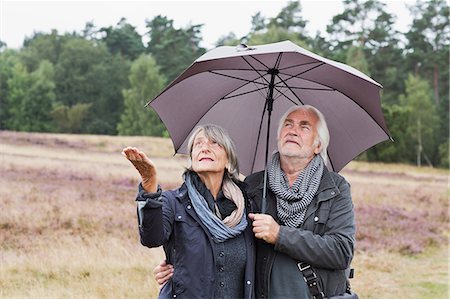 Senior couple under umbrella checking for rain Stock Photo - Premium Royalty-Free, Code: 649-07239708