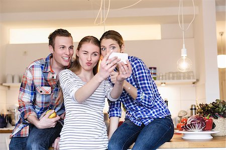 Three young people having fun taking photographs in the kitchen Foto de stock - Sin royalties Premium, Código: 649-07279561
