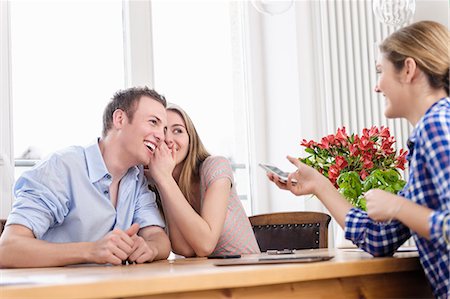 dialog at home man woman - Teenage girl whispering to young man with young woman watching Stock Photo - Premium Royalty-Free, Code: 649-07279563