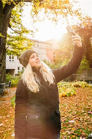 Young woman photographing herself in garden Stock Photo - Premium Royalty-Free, Code: 649-07279617