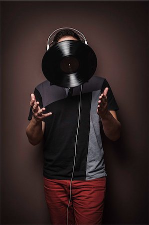 studio shot - Young man wearing headphones throwing vinyl record Stock Photo - Premium Royalty-Free, Code: 649-07279635