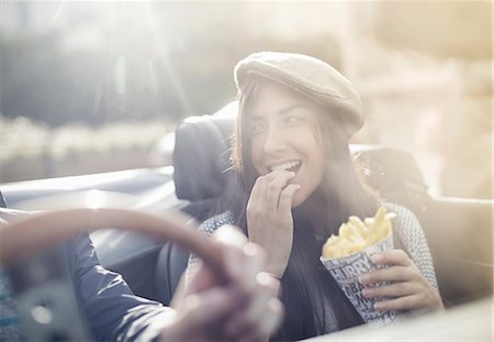 eating food people - Young couple in convertible, woman eating chips Stock Photo - Premium Royalty-Free, Code: 649-07279672