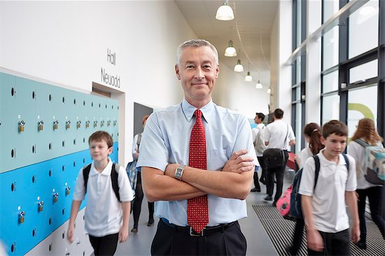 Portrait of male teacher with arms folded in school corridor Foto de stock - Sin royalties Premium, Código de la imagen: 649-07280062