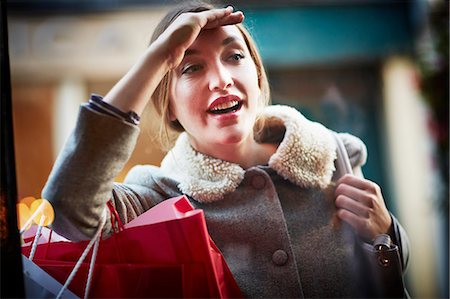 shopping bags fashion - Young woman carrying shopping bag, looking through window Stock Photo - Premium Royalty-Free, Code: 649-07280177