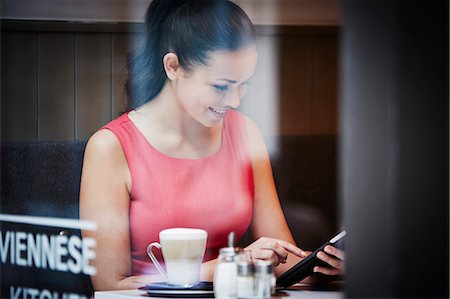 shop - Young woman sitting in cafe with digital tablet and hot drink Photographie de stock - Premium Libres de Droits, Code: 649-07280179