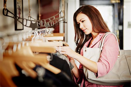 self indulgence - Young woman looking at selection of clothes on clothes rail Stock Photo - Premium Royalty-Free, Code: 649-07280204