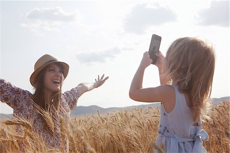 summer clothes - Girl taking photograph of mother in wheat field with arms open Stock Photo - Premium Royalty-Free, Code: 649-07280286