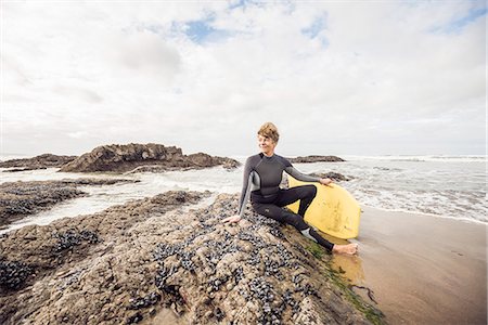 sunny portrait of woman one person looking at camera - Mature female bodyboarder sitting on rocks, Devon, UK Photographie de stock - Premium Libres de Droits, Code: 649-07280390