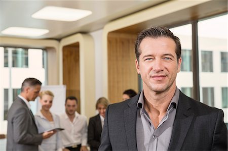 Businessman standing in front of colleagues Stock Photo - Premium Royalty-Free, Code: 649-07280474