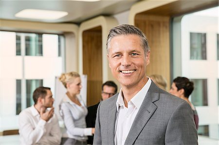 Businessman standing in front of colleagues Stock Photo - Premium Royalty-Free, Code: 649-07280473