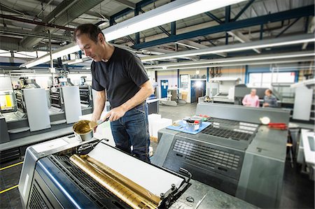 presse (imprimerie) - Worker applying gold ink to printing machine in print workshop Photographie de stock - Premium Libres de Droits, Code: 649-07280514