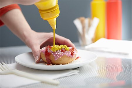 Woman squirting donut with ketchup and mustard Stock Photo - Premium Royalty-Free, Code: 649-07280597