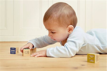 Baby lying on front playing with building blocks Stock Photo - Premium Royalty-Free, Code: 649-07280690