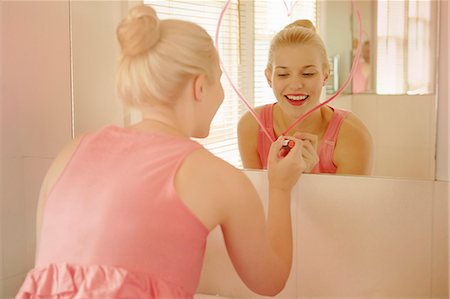 simsearch:649-07280746,k - Young woman in bathroom drawing heart shape on mirror with lipstick Photographie de stock - Premium Libres de Droits, Code: 649-07280715